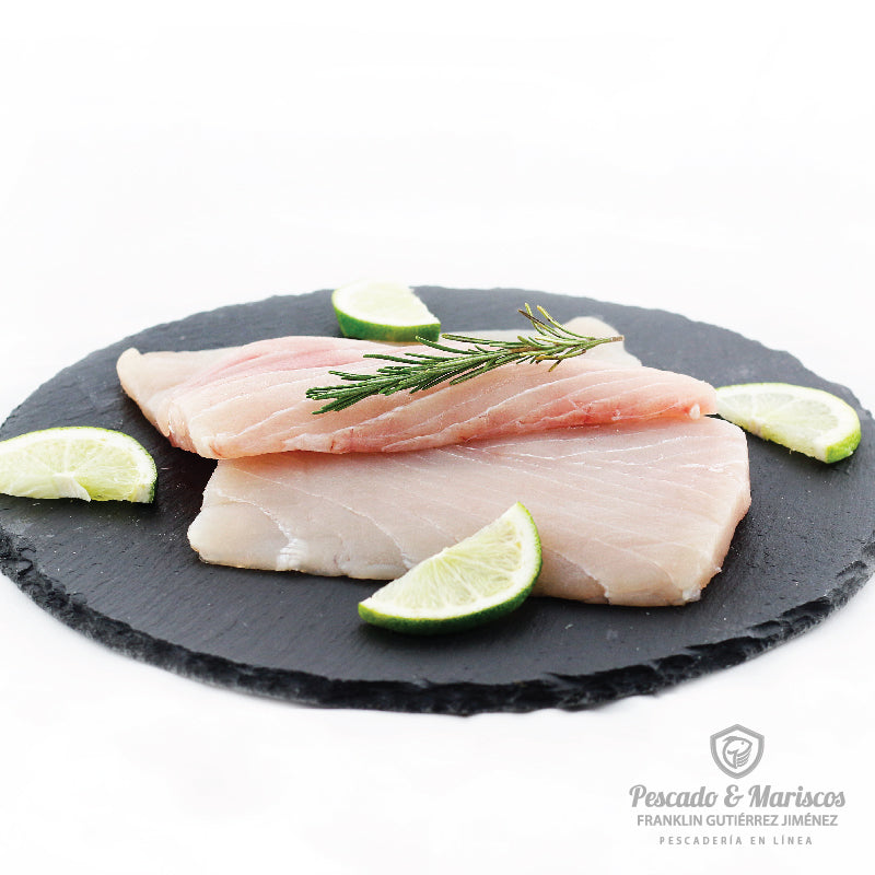 Dos filetes de marlin blanco decorados con rodajas de limón y una ramita de romero fresco.