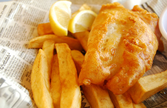 fish and chips con limon sobre hoja de periódico
