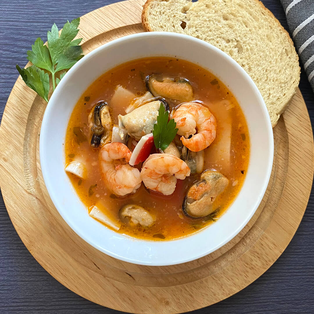 un plato de sopa de mariscos con camarones, calamar, surimi y almejas