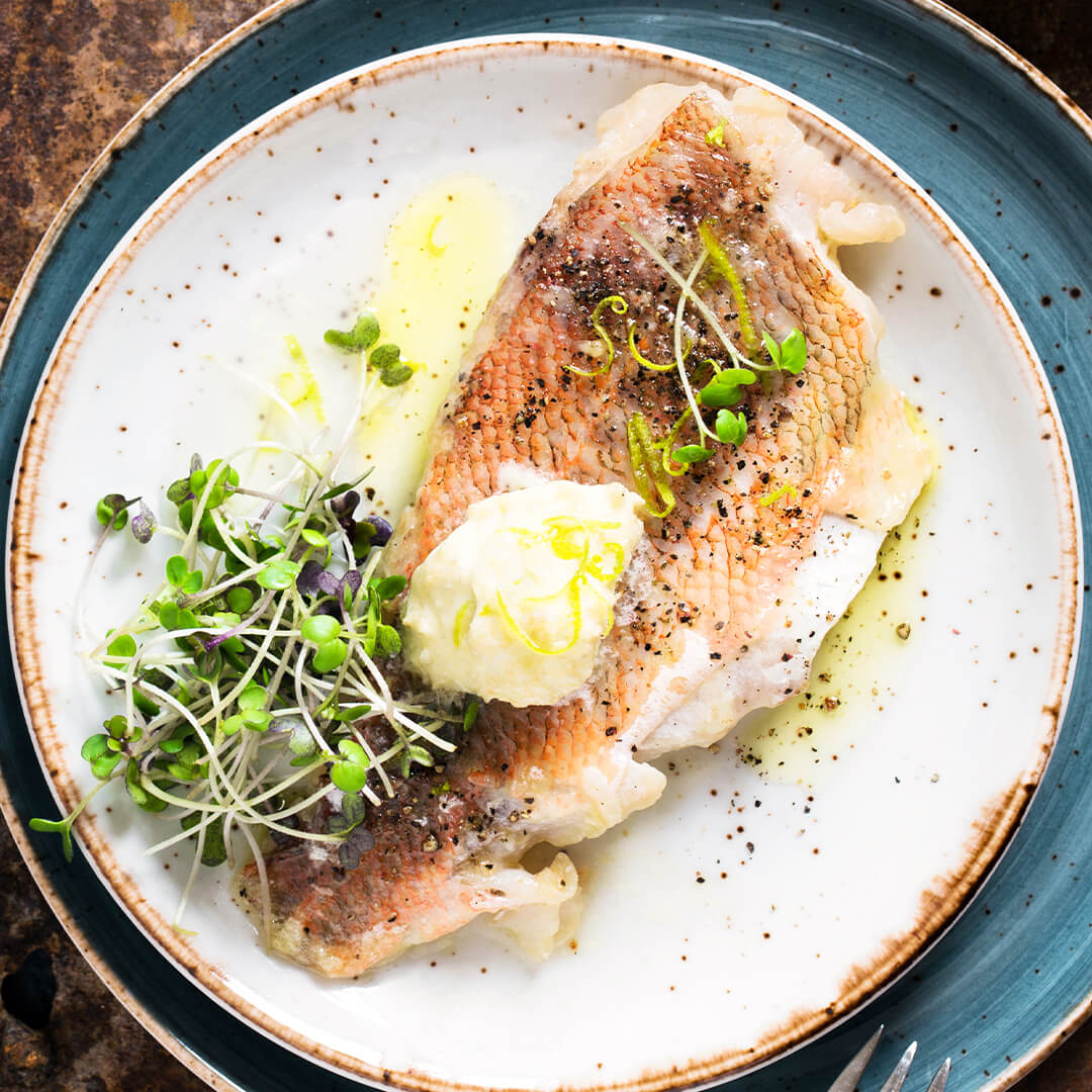 Un filete de pargo con piel dorado en mantequilla con microgreens