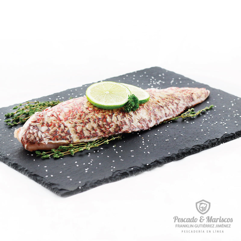 Un filete de pargo con piel decorado con tomillo y rodajas de limón 