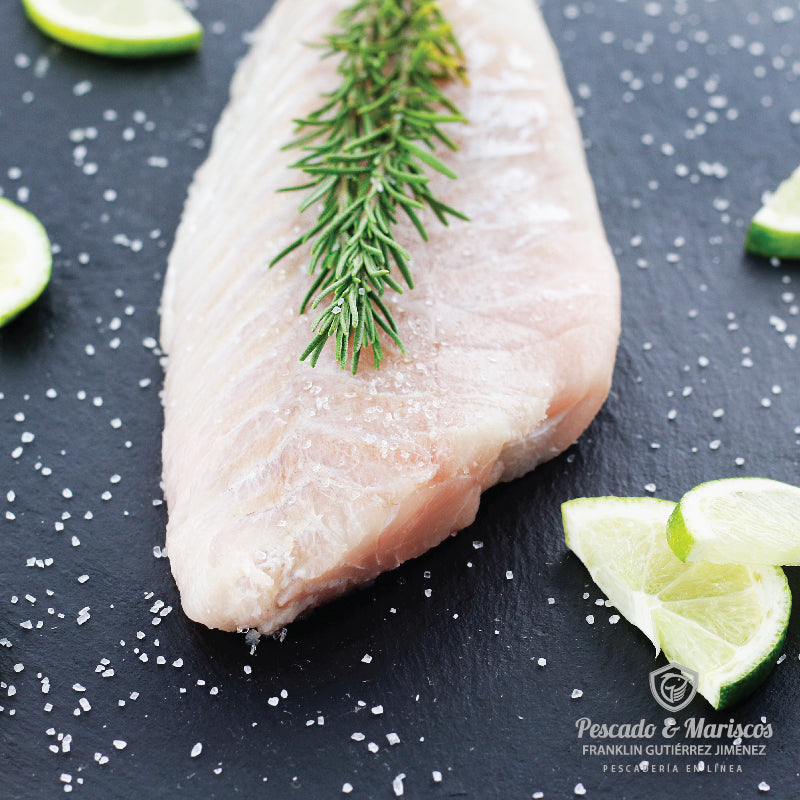 Un filete de corvina decorado con romero y rodajas de limón 